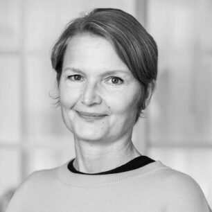 En person med kort hår ler mot kameran i en svartvit bild.